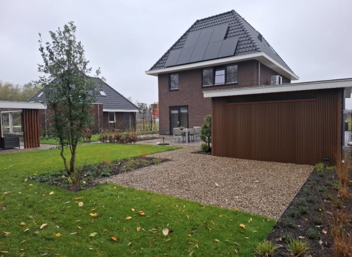 Ruime tuin bij woning met gazon, grindvlak, borders en houten gevelafwerking