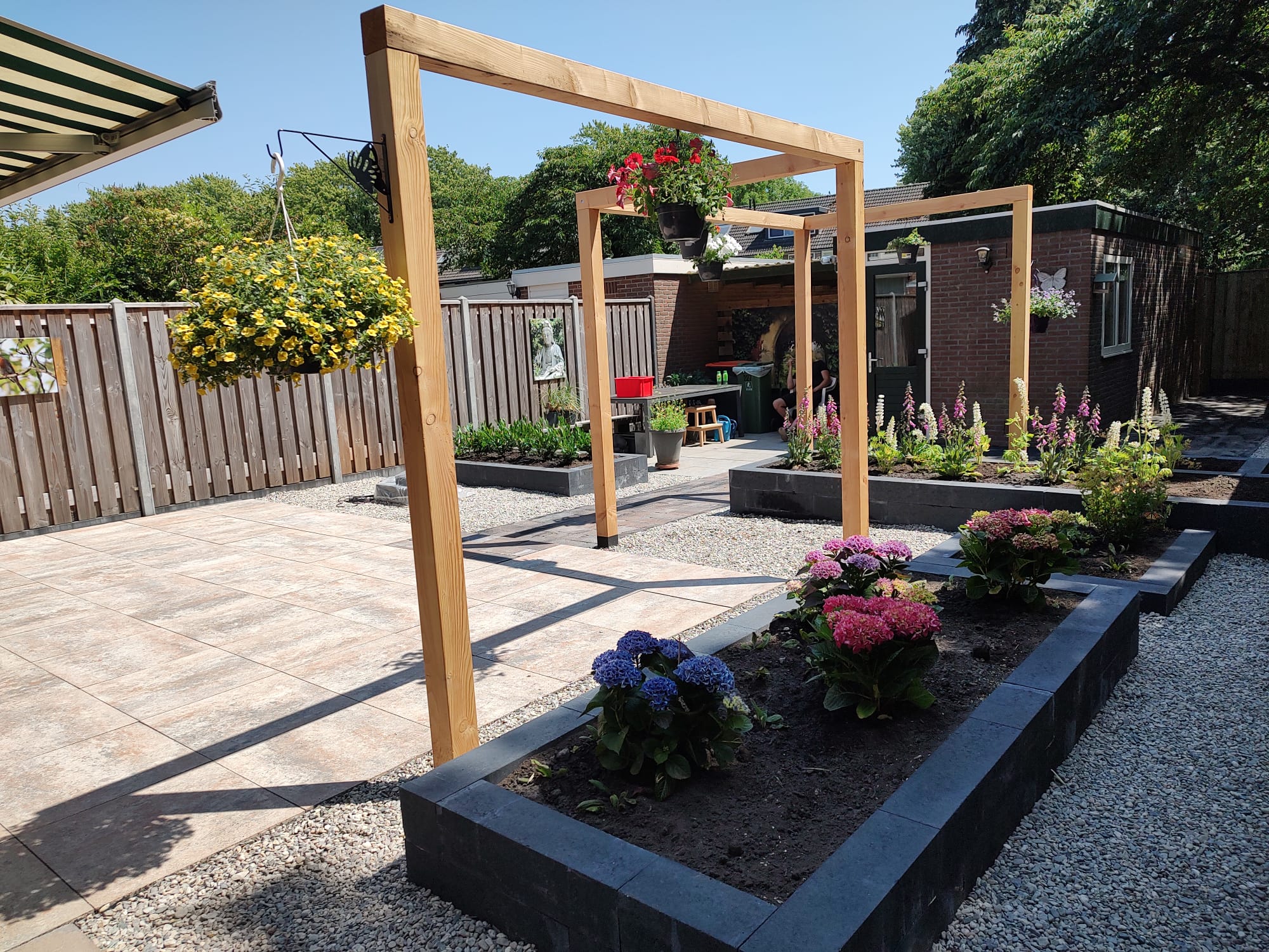 Tuin met houten pergola's, bloeiende borders, terras en grindpaden